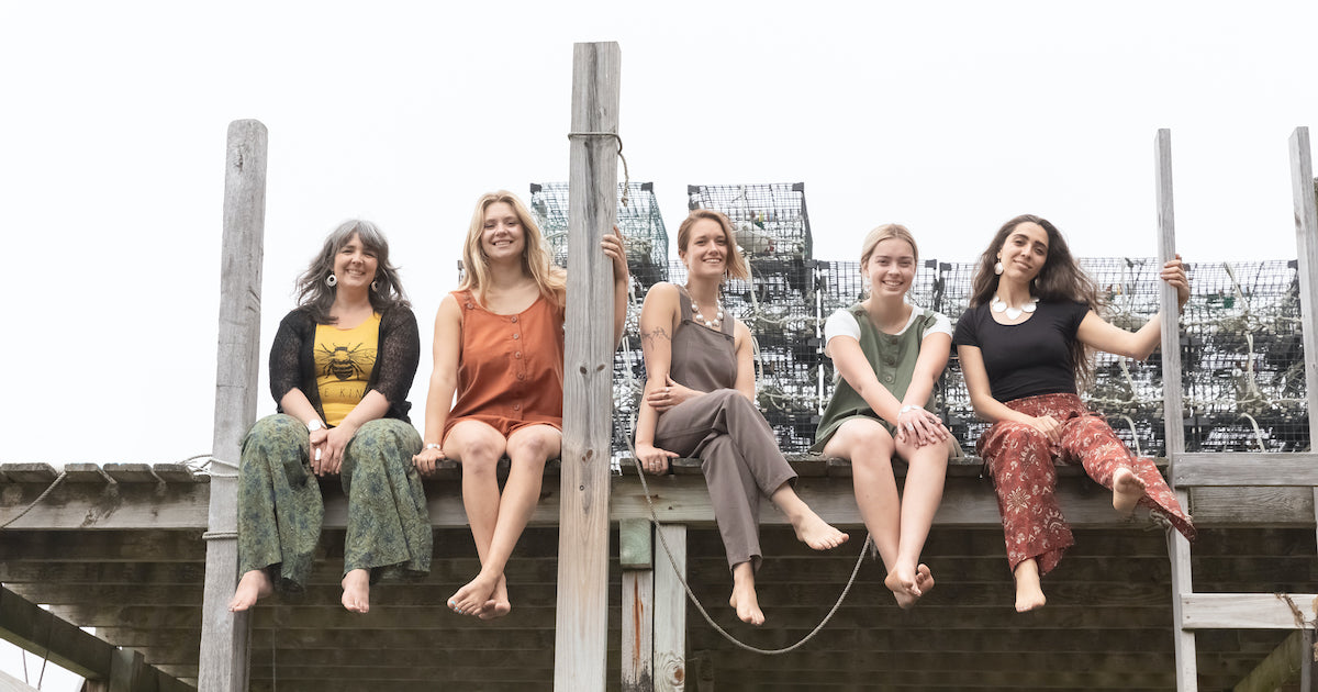 A group of beautiful women on a dock shot from below in hippie outfits with lobster traps in the background