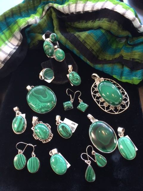 a pile of polished malachite gemstone jewelry set in sterling silver