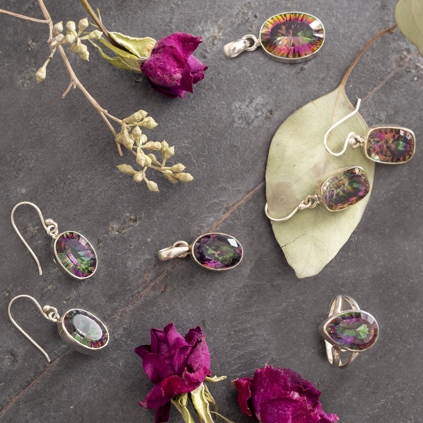 a selection of shining mystic topaz jewelry surrounded by pink flower petals