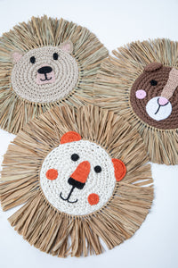 Three macrame wall hanging in the shape of a animal faces with the manes made from palm fronds.
