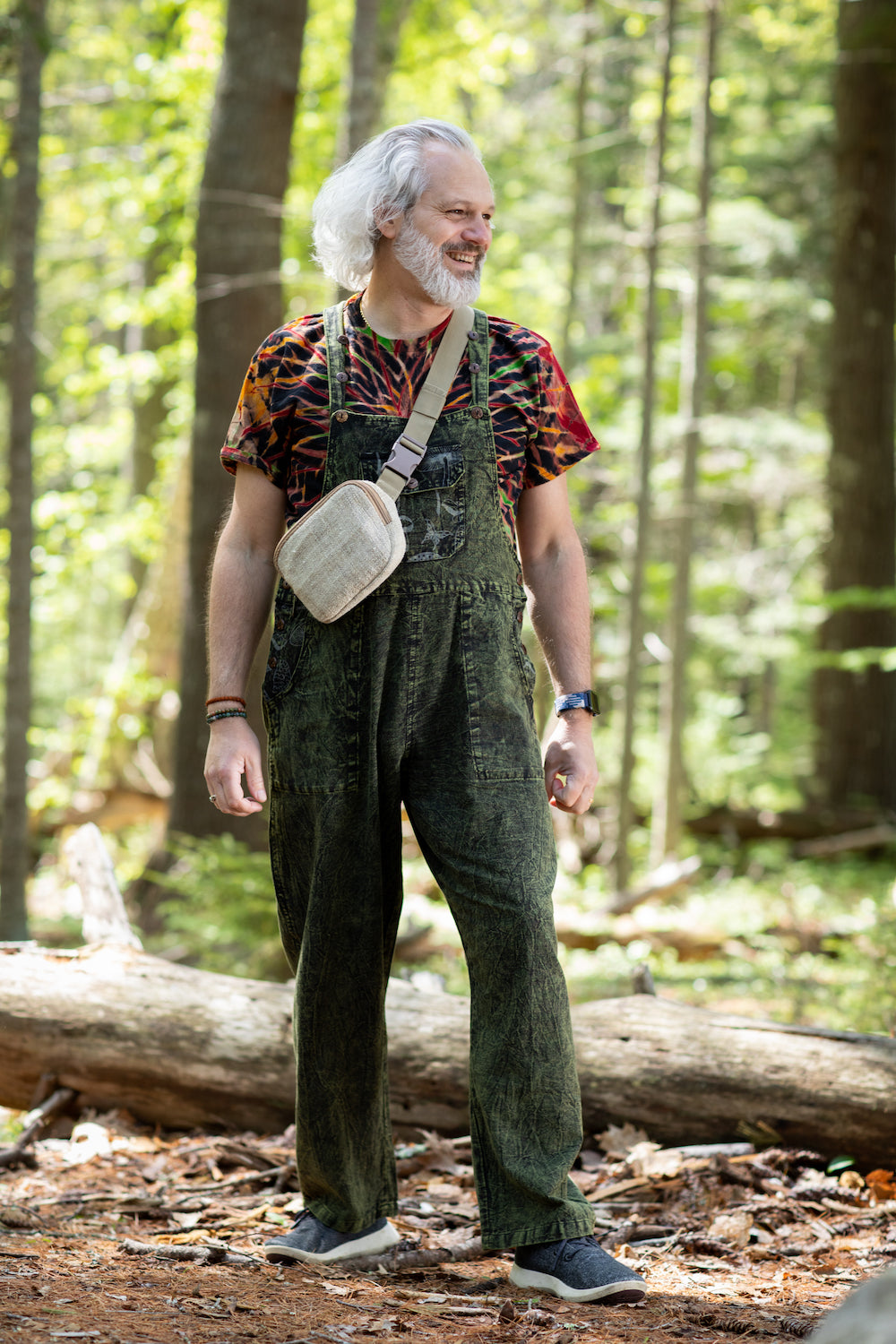Older man in mycologist inspired mushroom overalls in the forest
