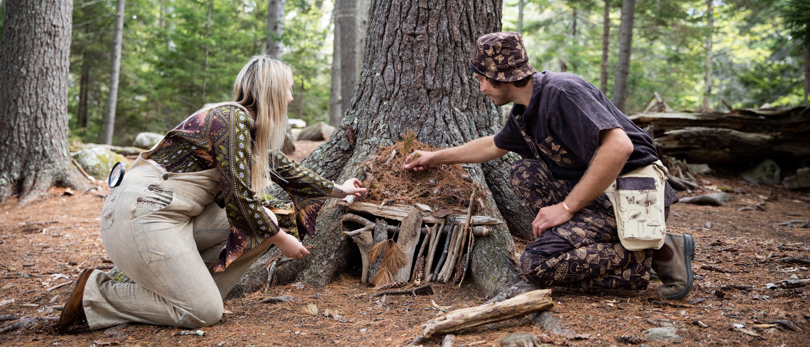 Two mushroom foragers building a fairy house in matching mushroom overalls and mushroom jumpsuit outfits building a fairy house in the forest
