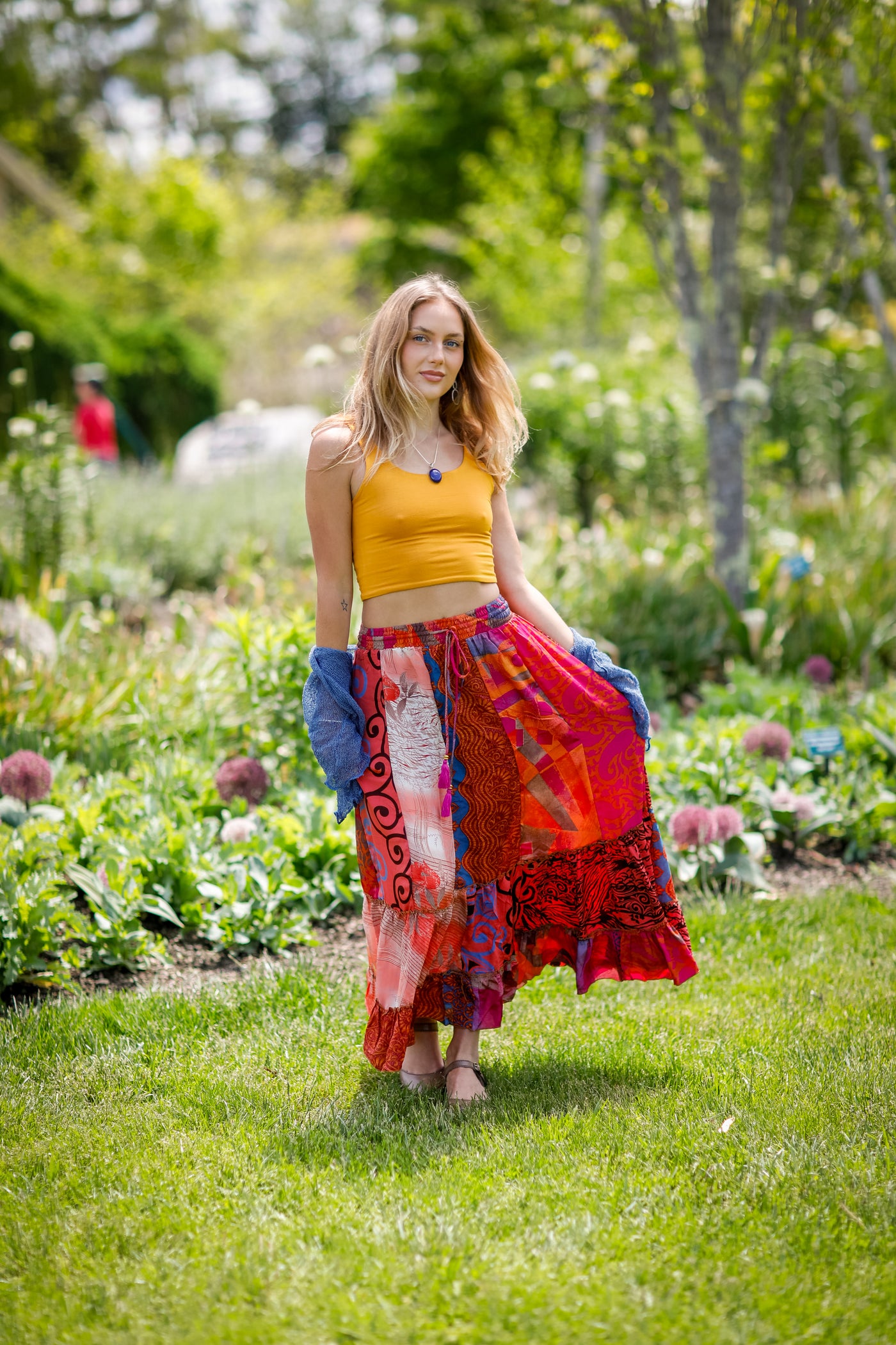 Woman in silky patchwork skirt in a garden