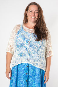 Sarah wearing a ivory lightweight knitted poncho with a solid pattern.
