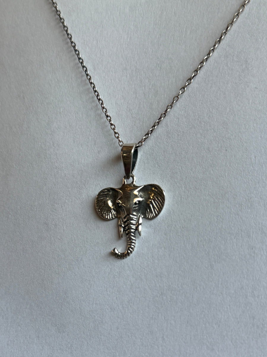 Silver elephant pendant on a chain against a light gray background
