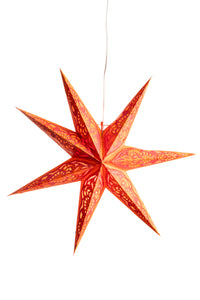 A red paper star lantern hanging in front of a white backdrop. 