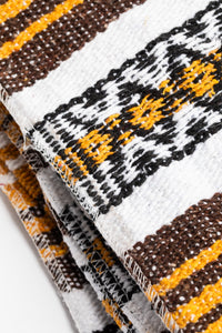 Woven recycled yarn blanket with yellow, brown, and white patterns on a white background