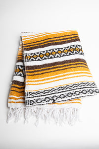 Woven recycled yarn blanket with yellow, brown, and white patterns on a white background