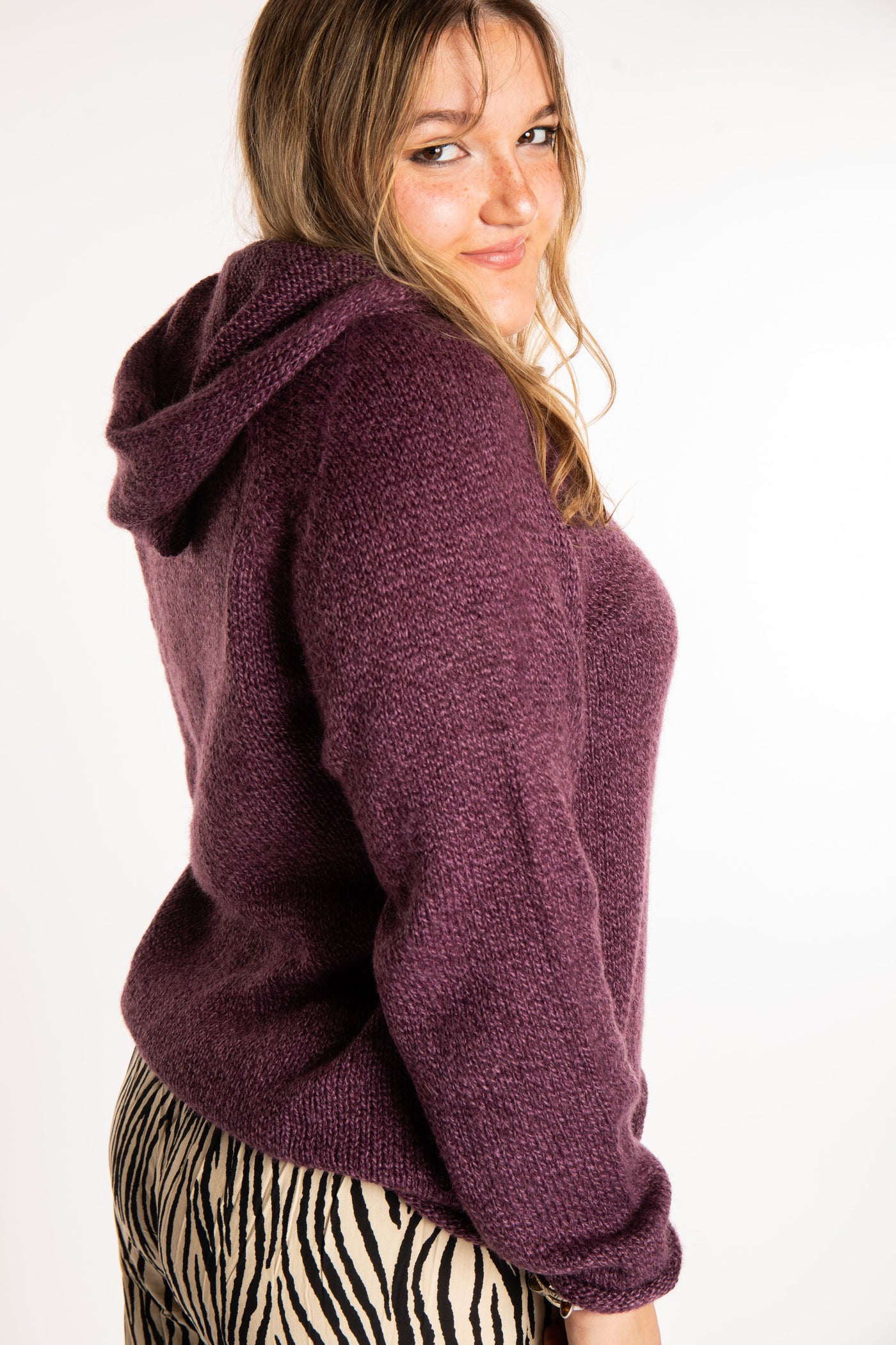 Emma is wearing a size L hooded alpaca sweater in Plum