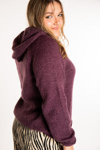 Emma is wearing a size L hooded alpaca sweater in Plum