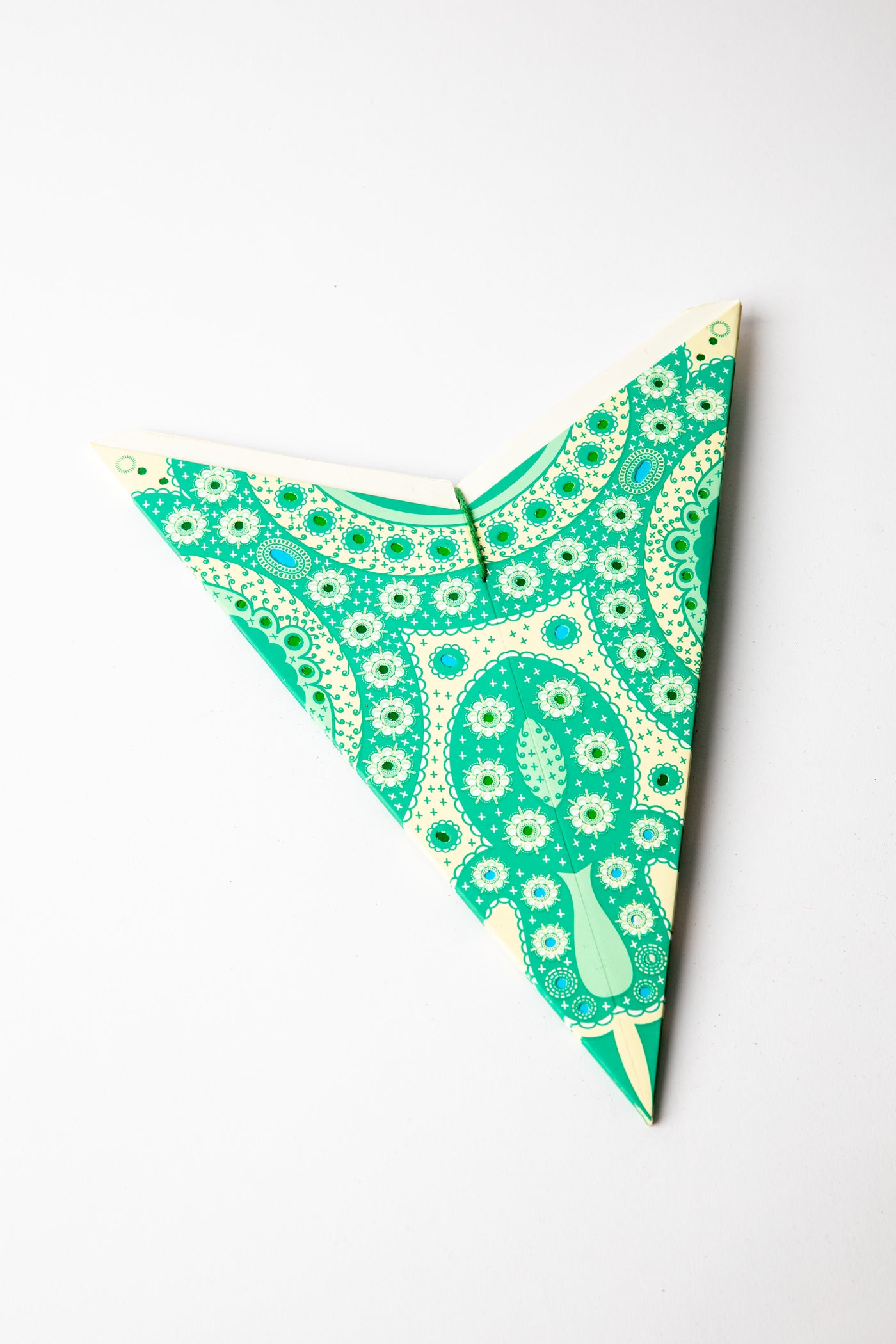 Green embroidered paper star folded up, out of the package