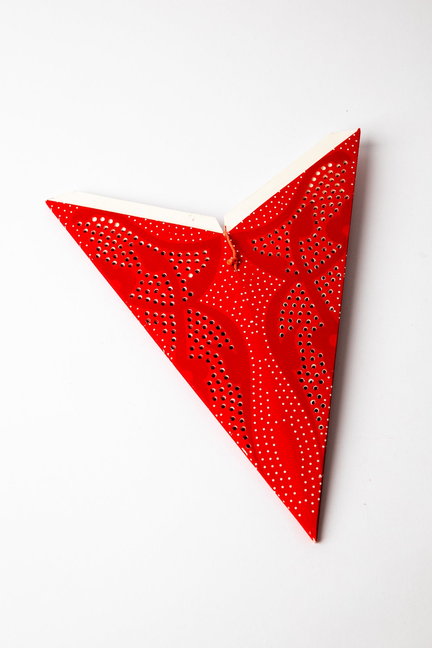 Red dotted embroidered paper star folded up, out of the package