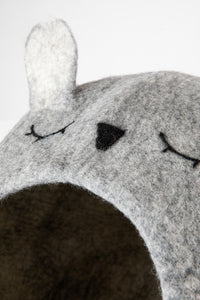 Closeup of a a light gray felted cat cave with closed eyed, nose, and ear visible