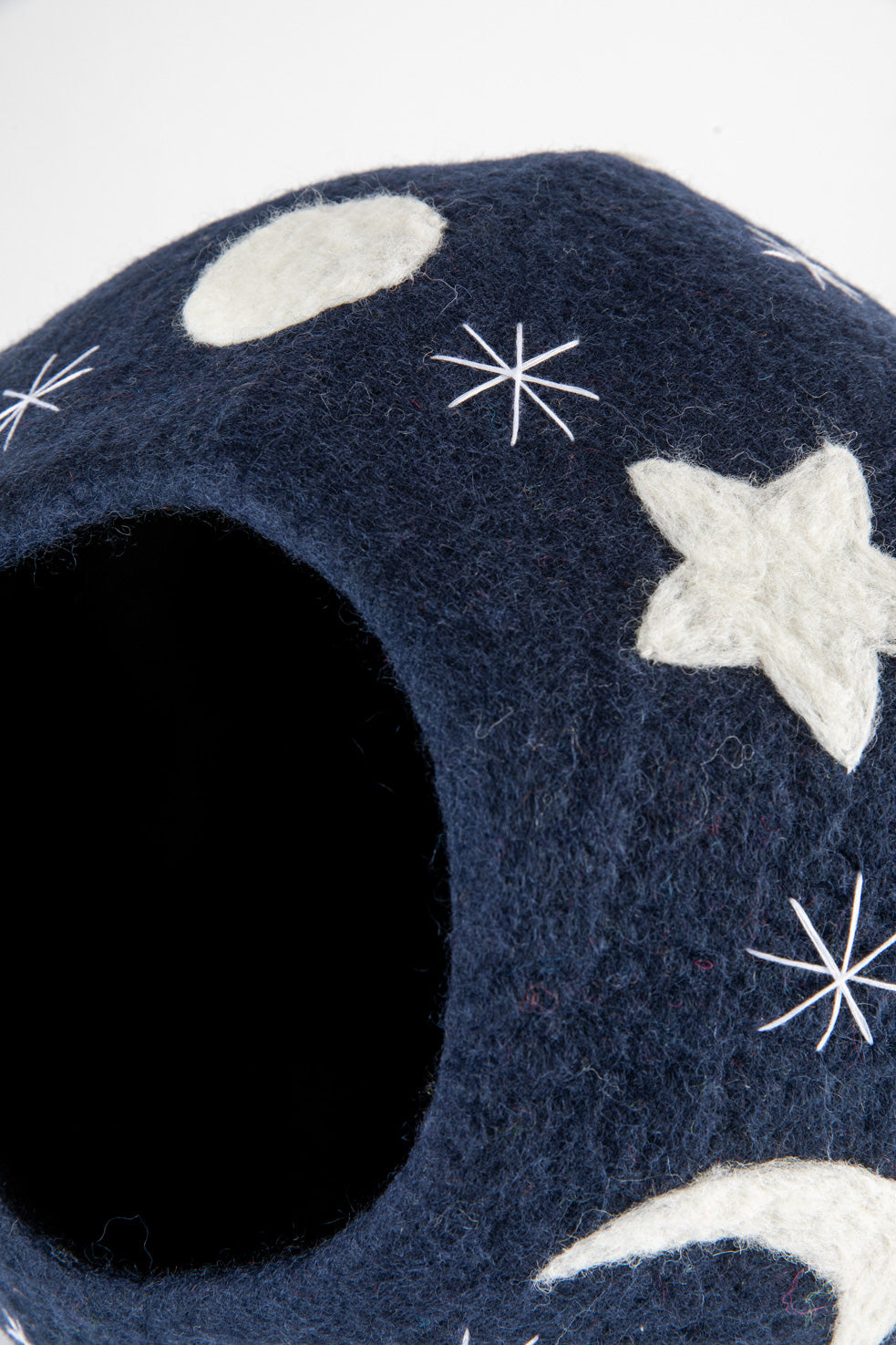 Closeup of a navy cat cave with embroided stars and felt moon and star shapes