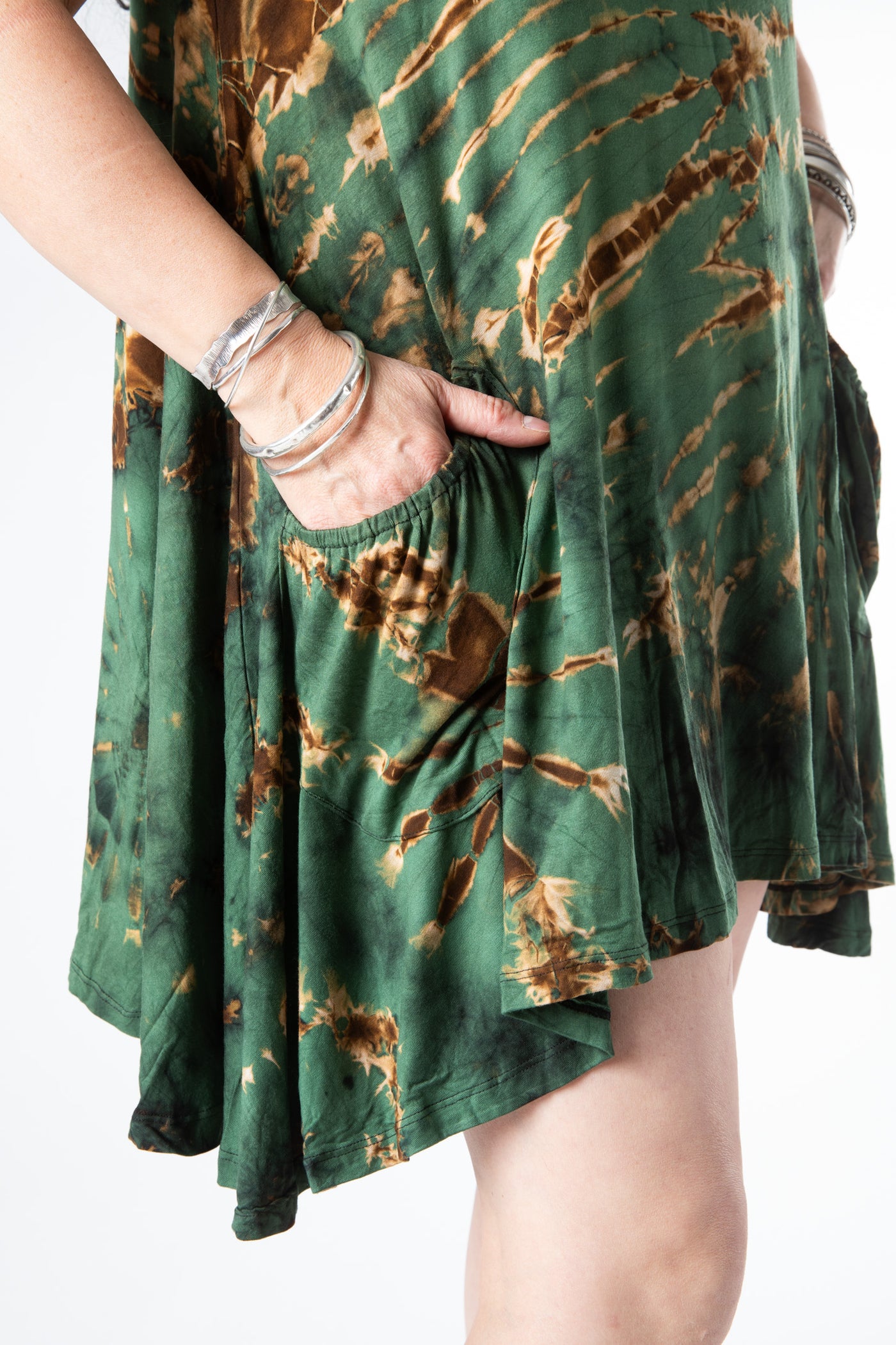 Close up image of the pocket on this green tie dye dress on a woman with her hand in the pocket wearing sterling silver bracelets 