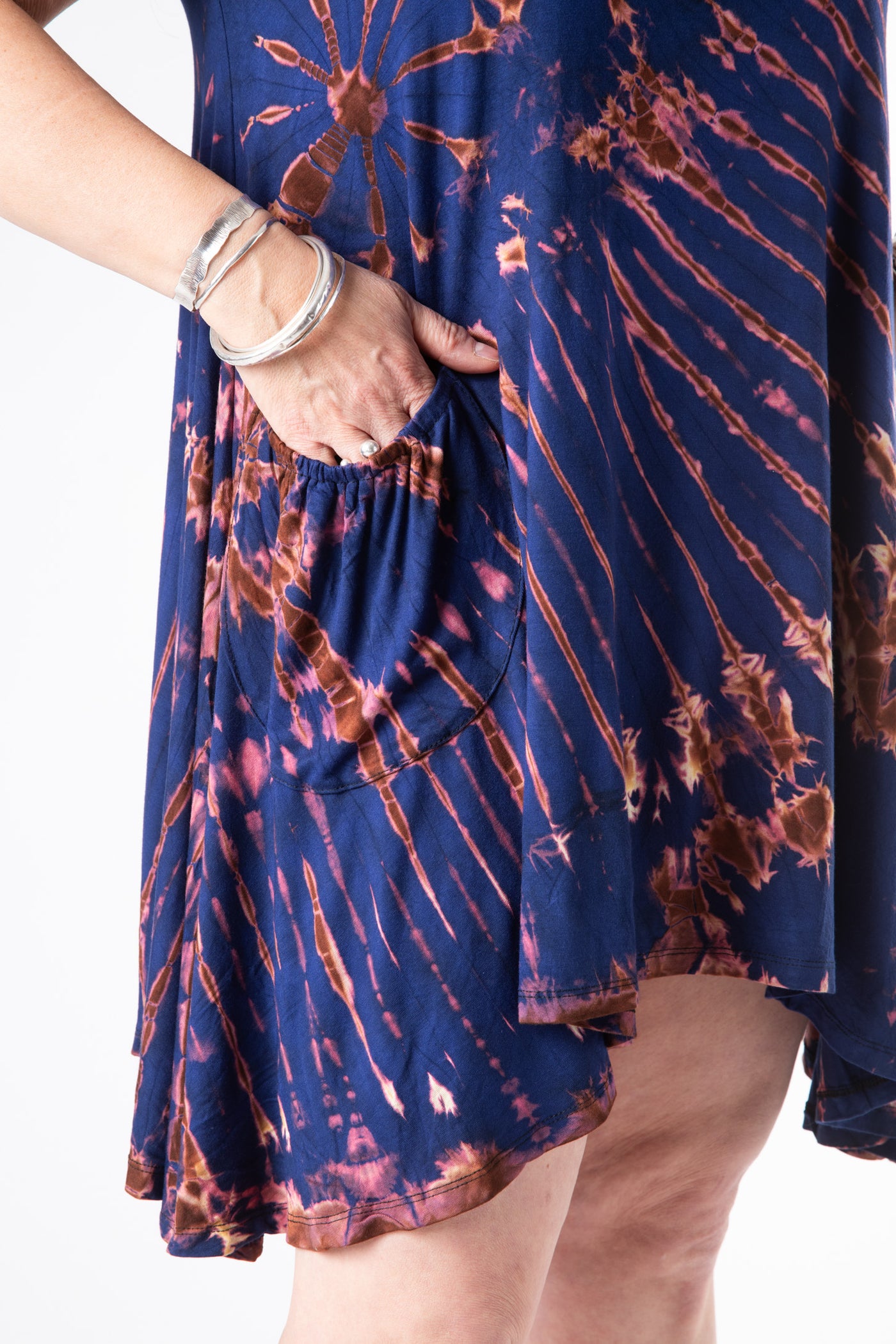A detailed image of the pockets of this blue tie dye dress on a female model with her hand in the pocket wearing sterling silver bracelets 