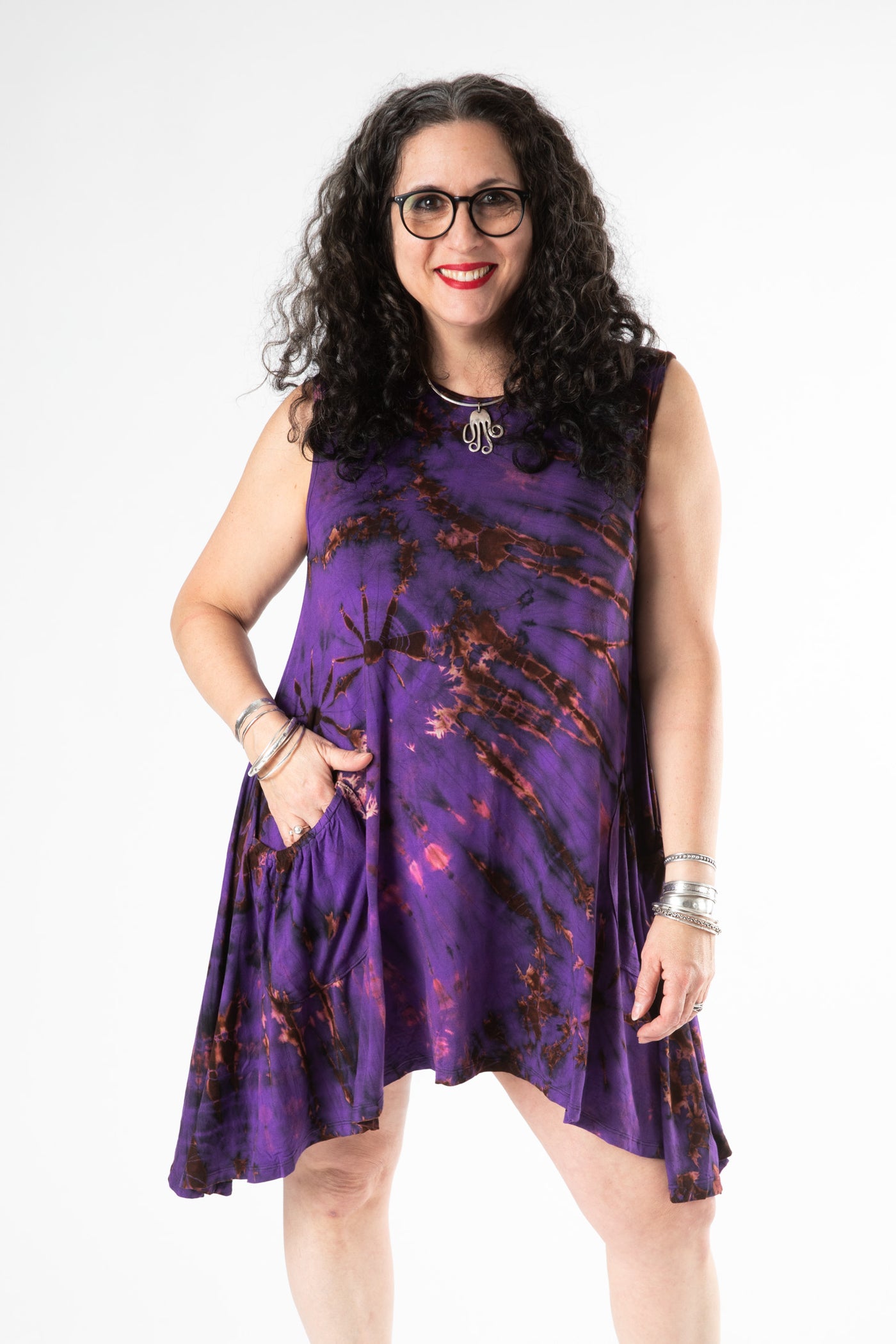 Happy curly haired woman wearing a purple sleeveless tie dye dress and sterling silver jewelry 