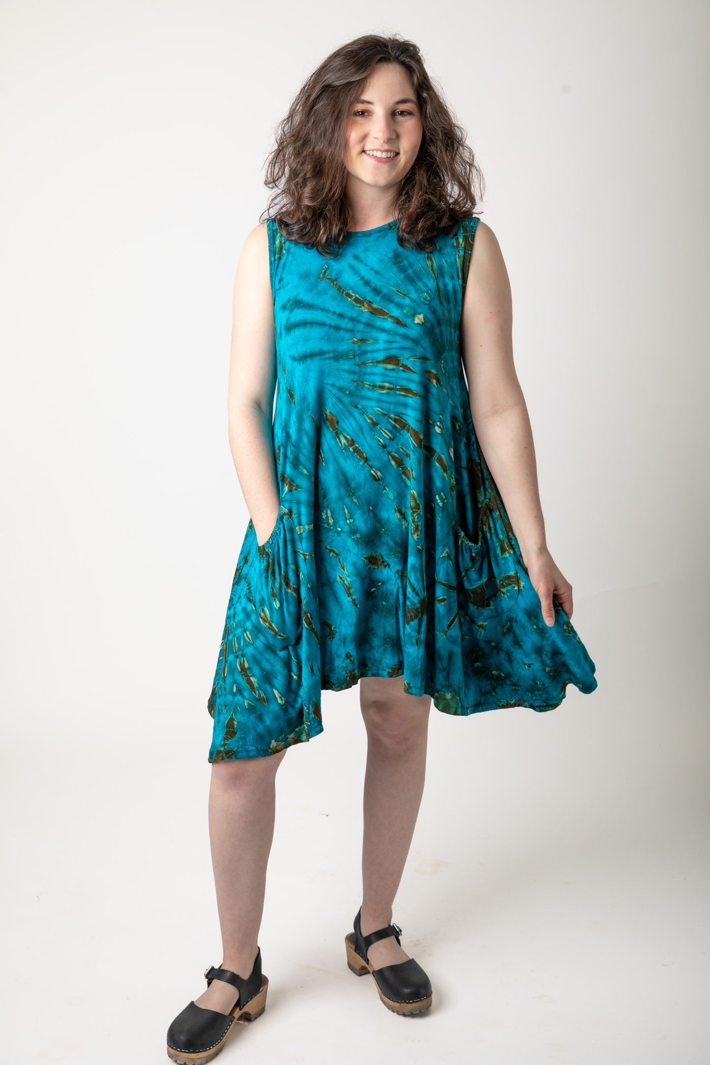 Pretty brunette girl wearing a turquoise tie dye dress with black shoes 