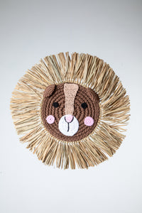 Macrame wall hanging in the shape of a squirrel's face with a mane made from palm fronds.