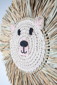 Macrame wall hanging in the shape of a bear's face with a mane made from palm fronds.
