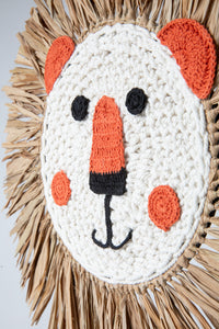 Macrame wall hanging in the shape of a lion's face with a mane made from palm fronds.