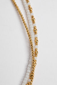 layered beaded necklace in white on white background