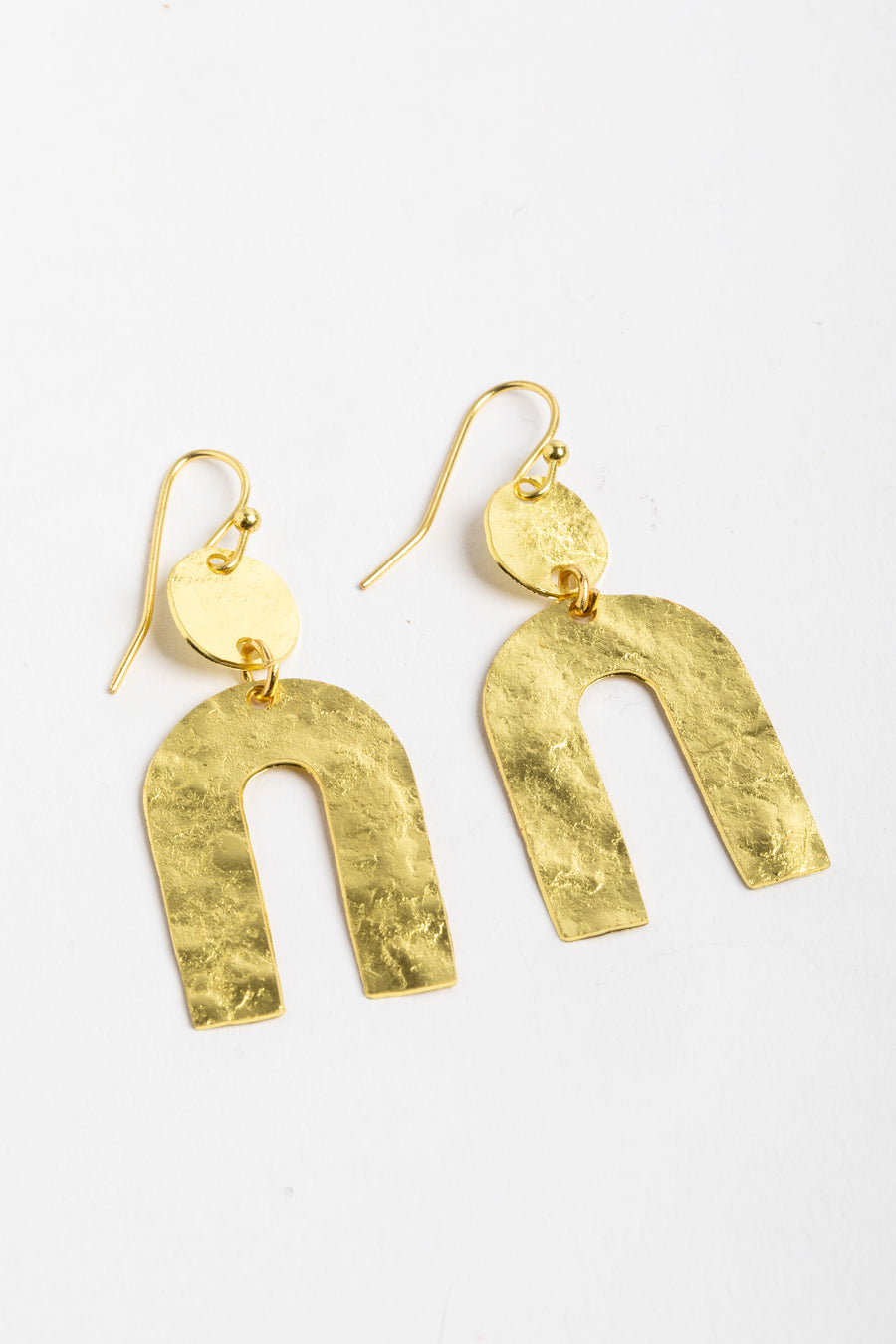 gold sculptural statement earrings on white background