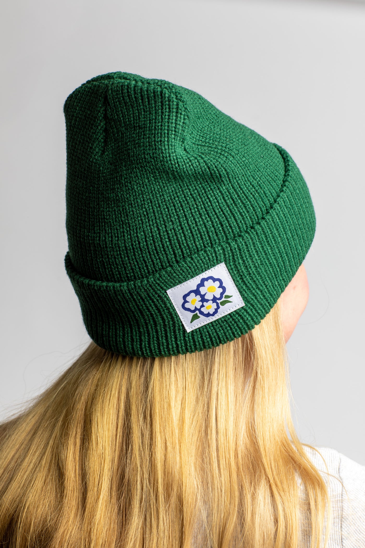 Talia wearing the Forest Green knit acrylic beanie with a floral patch