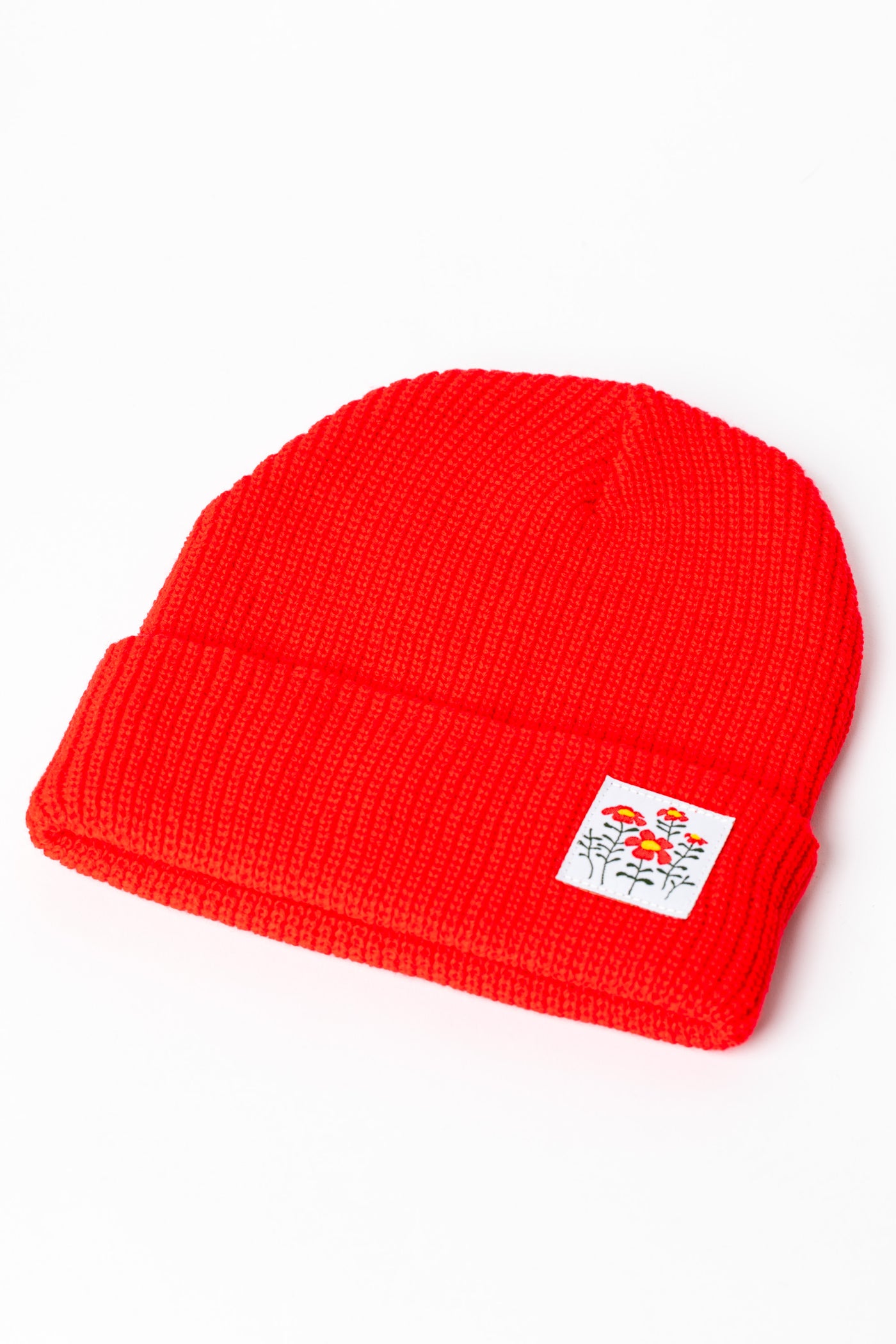 Detail of Orange Red knit acrylic beanie with a wildflower patch