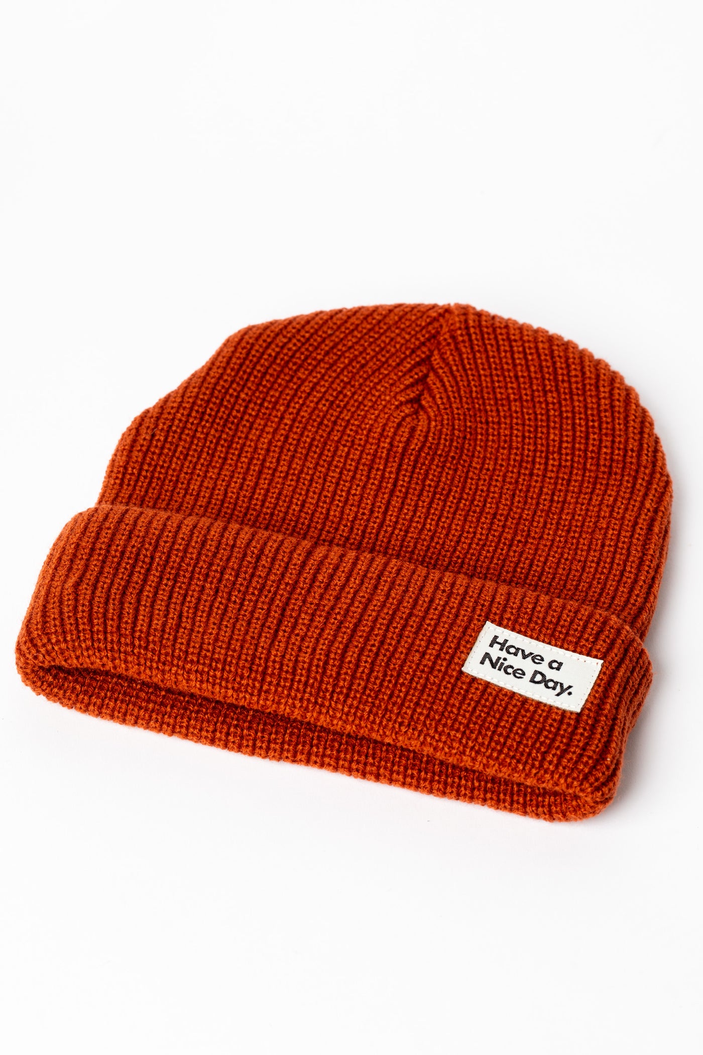 Rust orange knit acrylic beanie with a "Have a Nice Day" patch