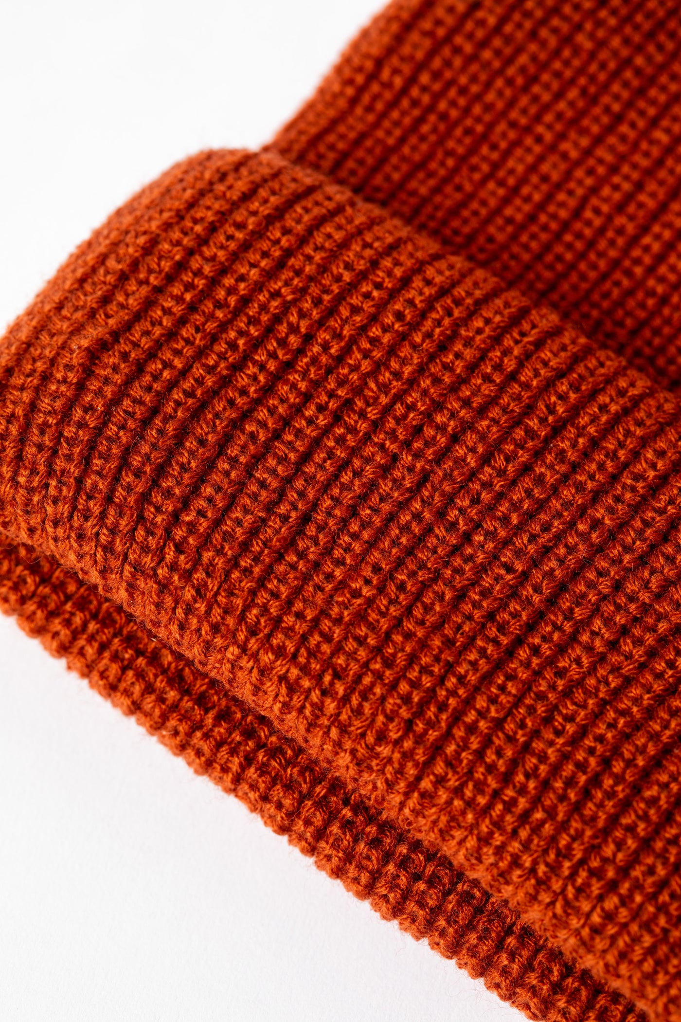Detail of rust orange knit acrylic beanie with a "Have a Nice Day" patch