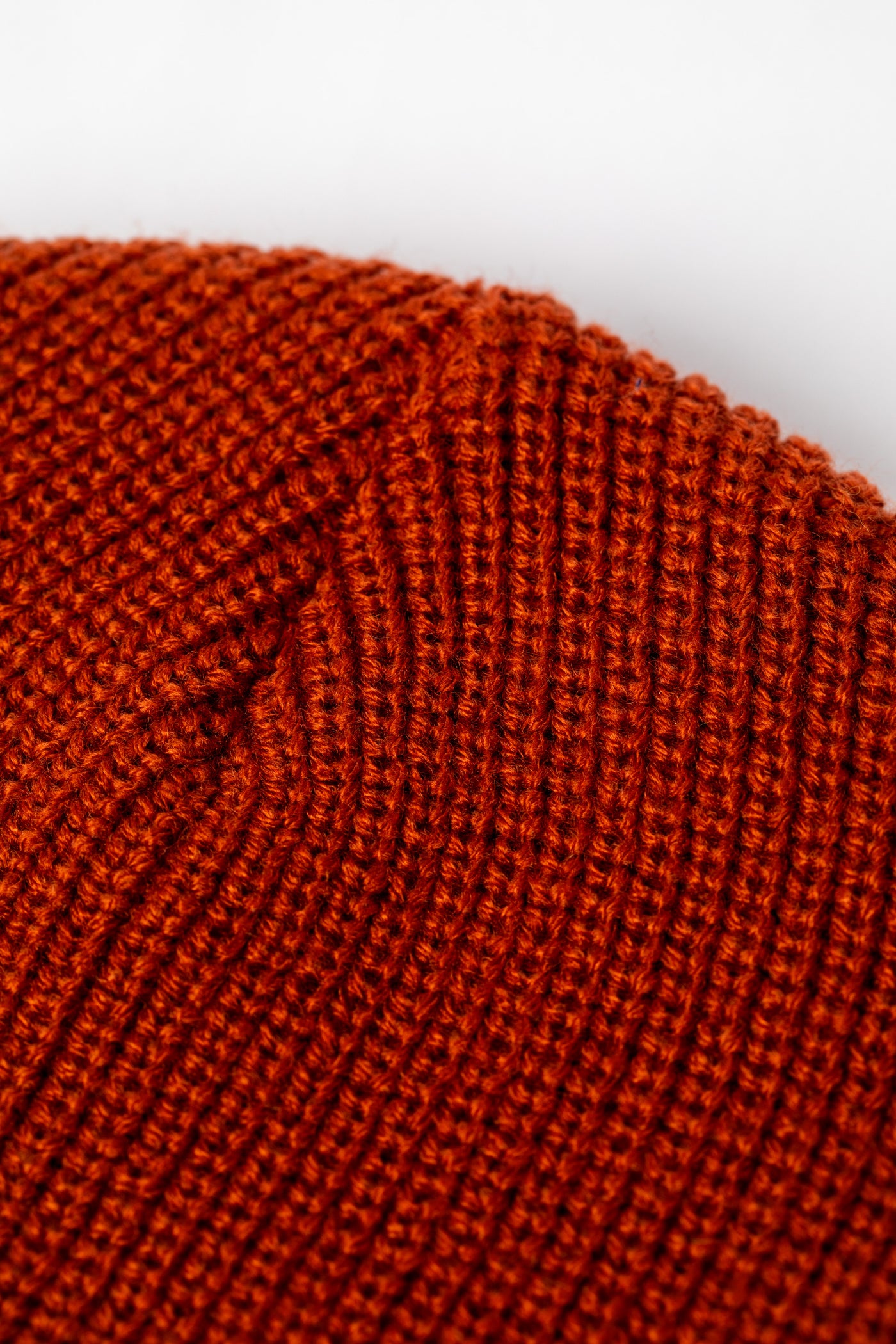 Detail of rust orange knit acrylic beanie with a "Have a Nice Day" patch