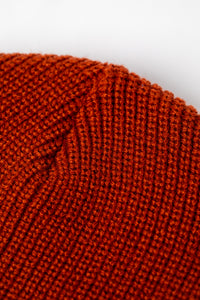 Detail of rust orange knit acrylic beanie with a "Have a Nice Day" patch