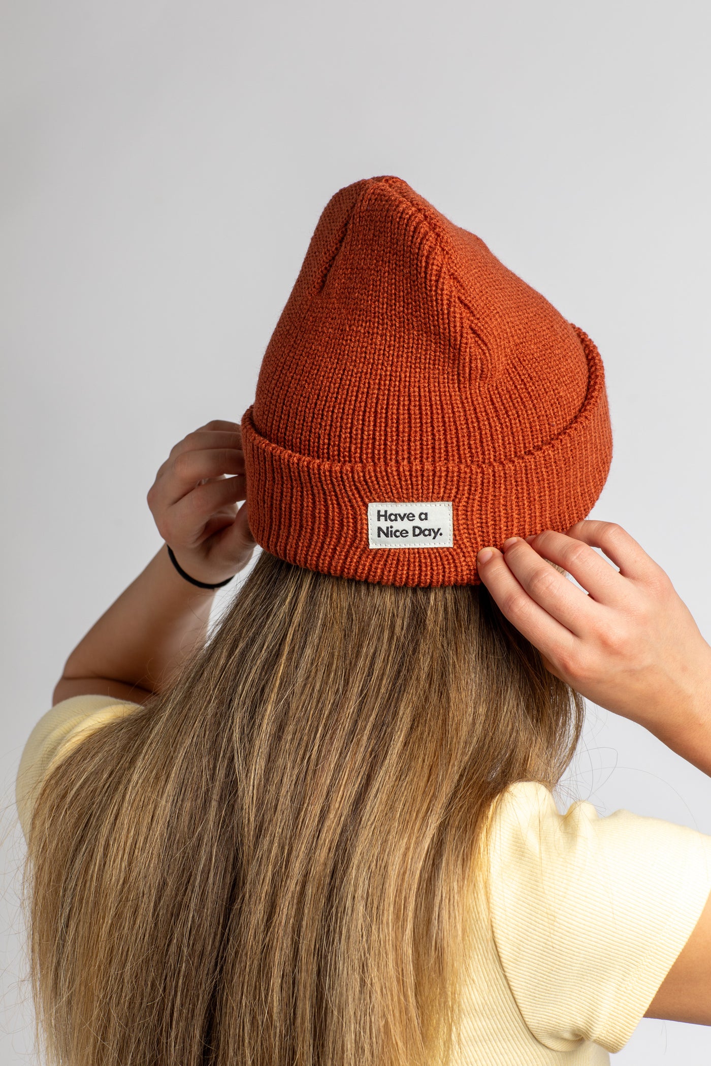Lea wearing the Rust acrylic beanie that says "Have a Nice Day"