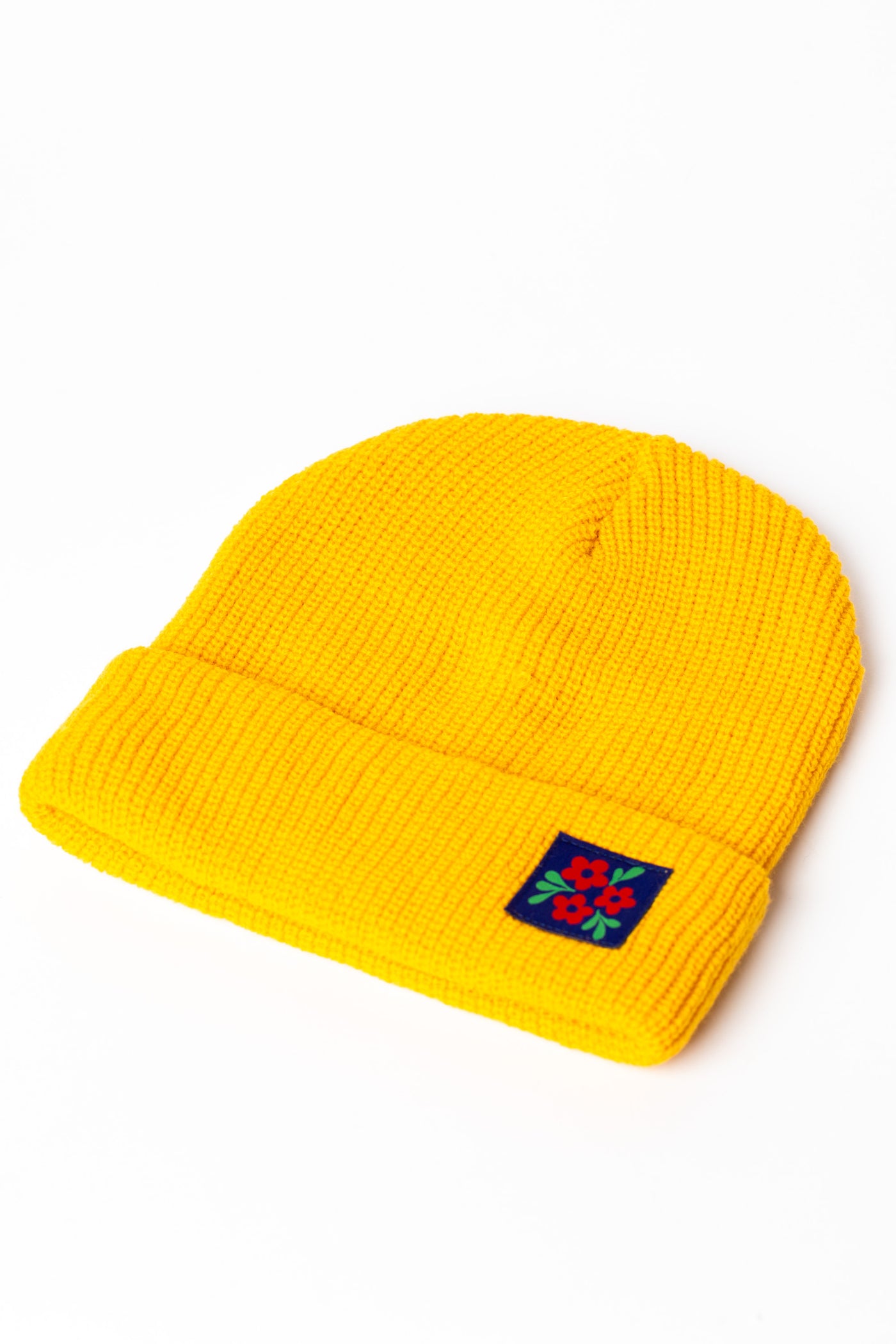 Detail of Yellow knit acrylic beanie with a floral patch