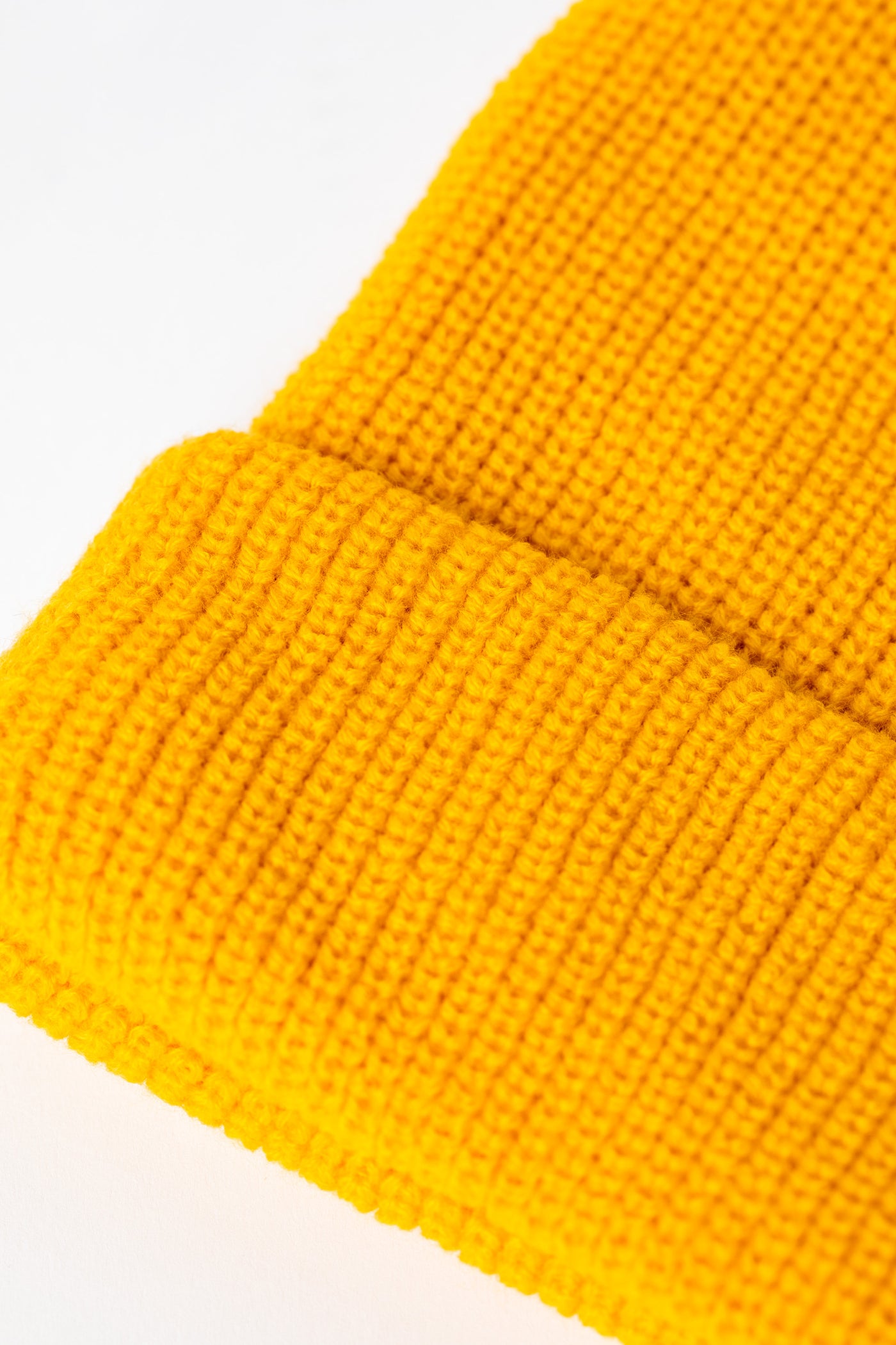 Detail of Yellow knit acrylic beanie with a floral patch
