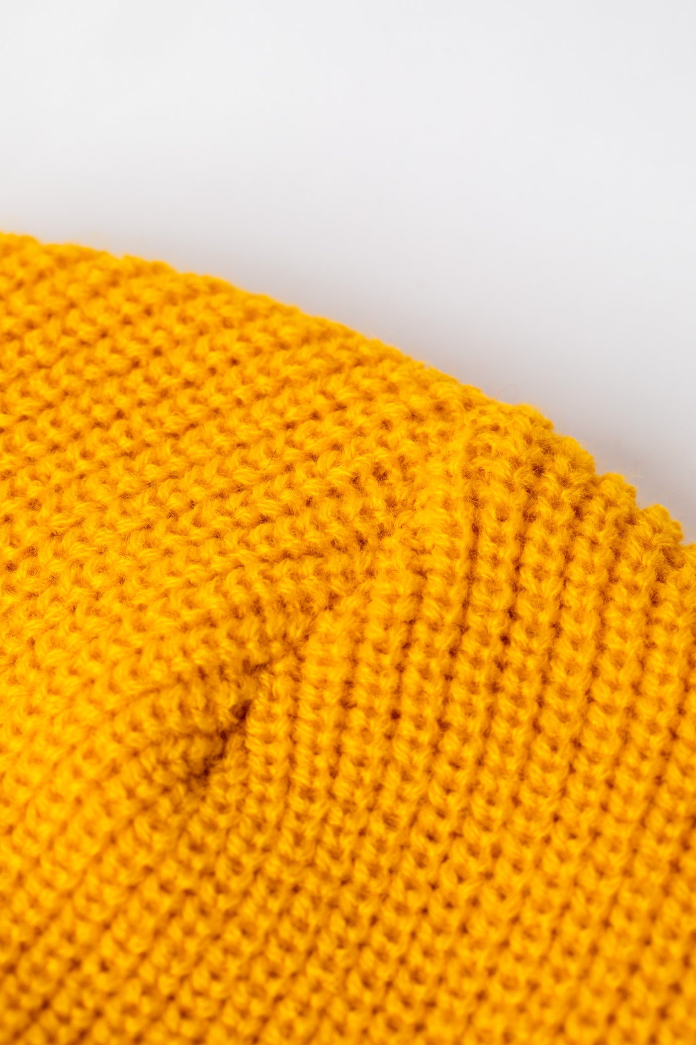 Detail of Yellow knit acrylic beanie with a floral patch