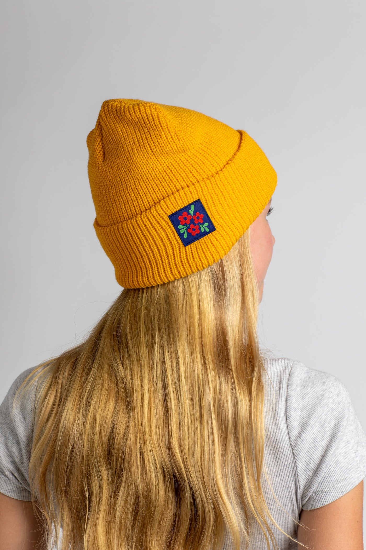 Talia wearing the Yellow knit acrylic beanie with a floral patch