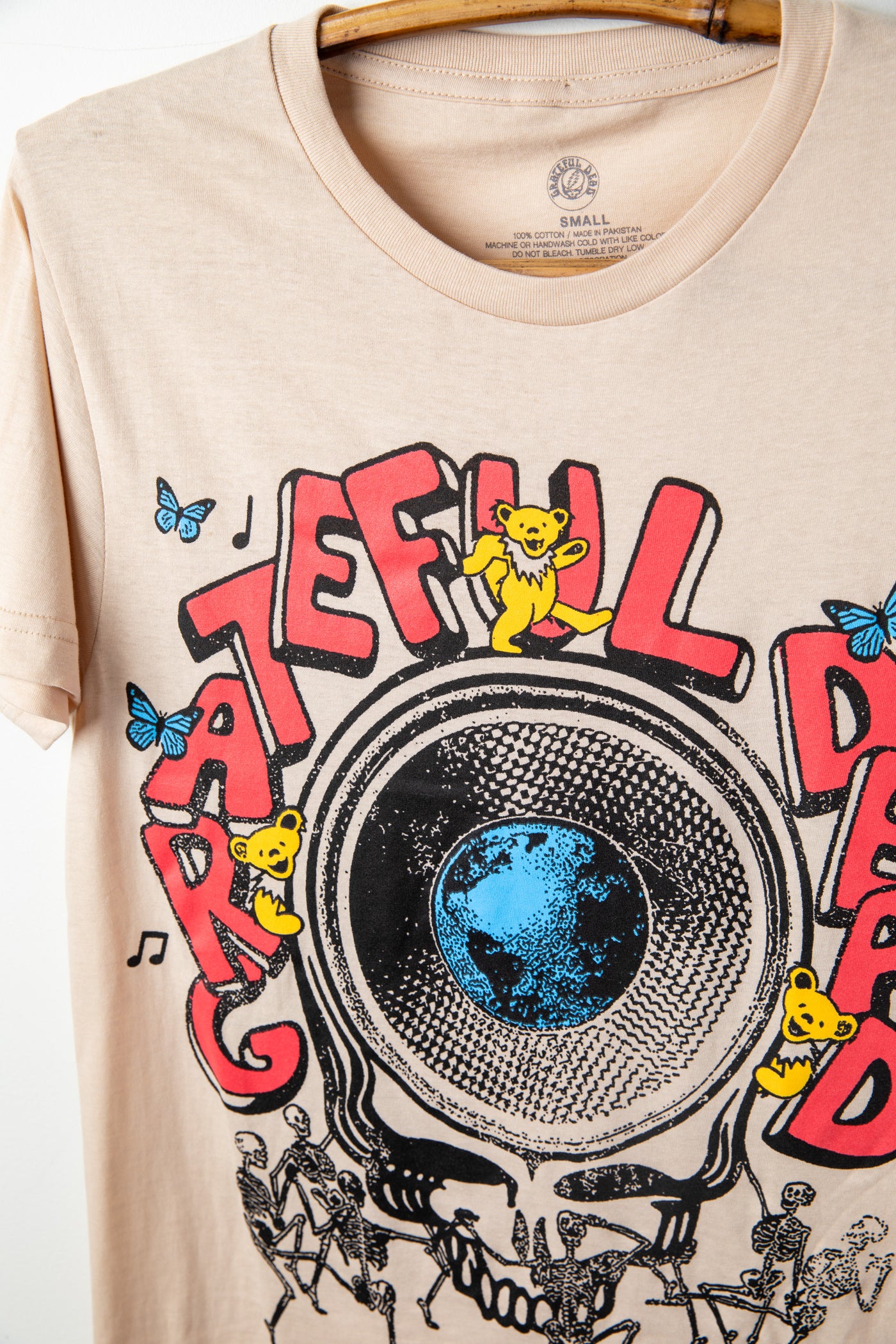Beige t-shirt with Grateful Dead, Steal Your Face graphic.