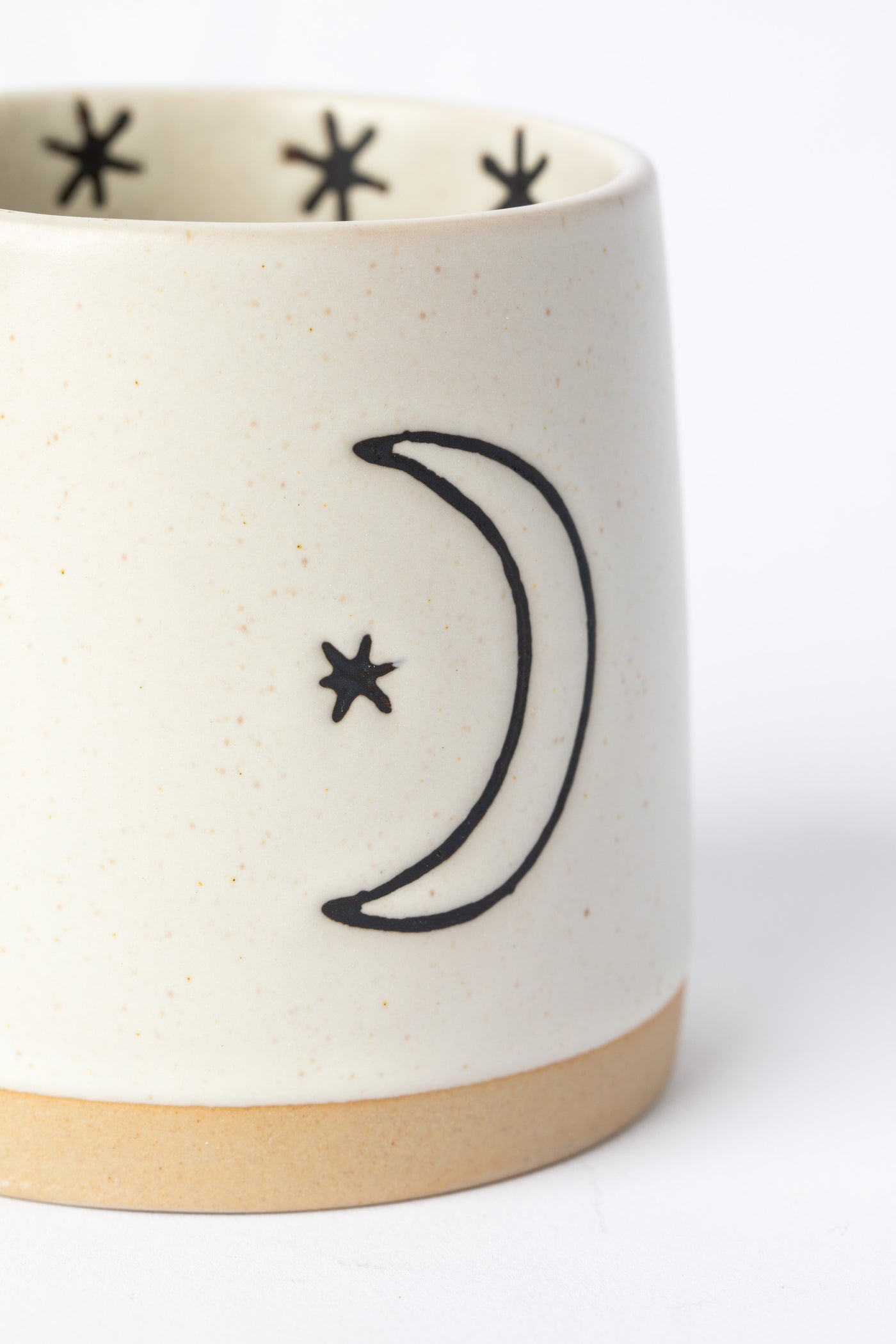 Close-up of crescent moon design in black on cream ceramic on Crescent Moon and Sun Mug.