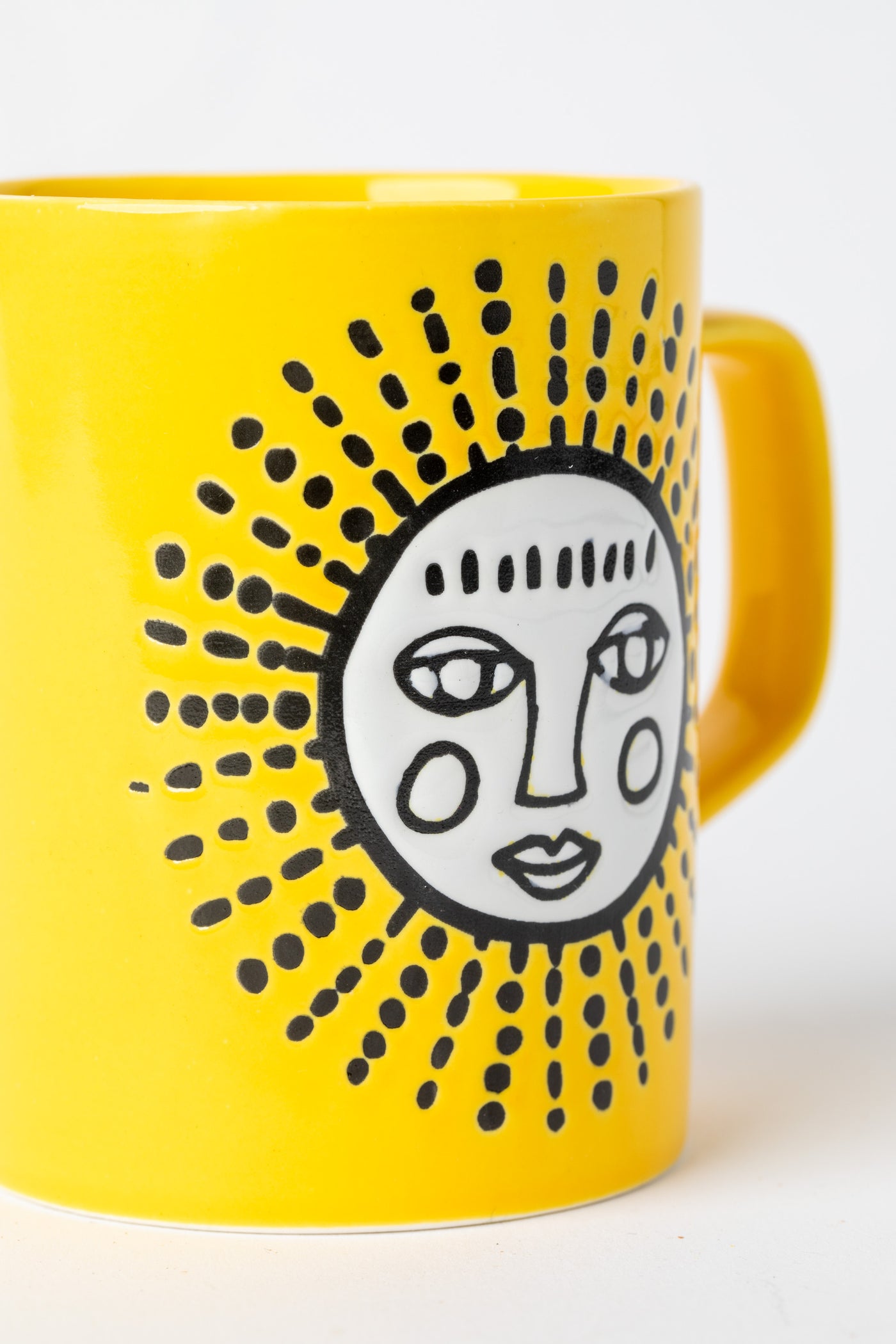 Yellow Sun Cuppa Color Mug with embossed face design.
