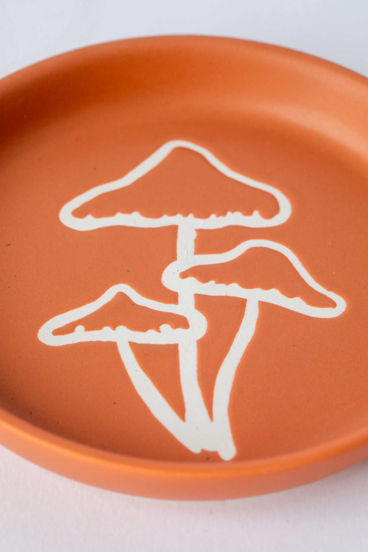 Terracotta coaster with white mushroom illustration