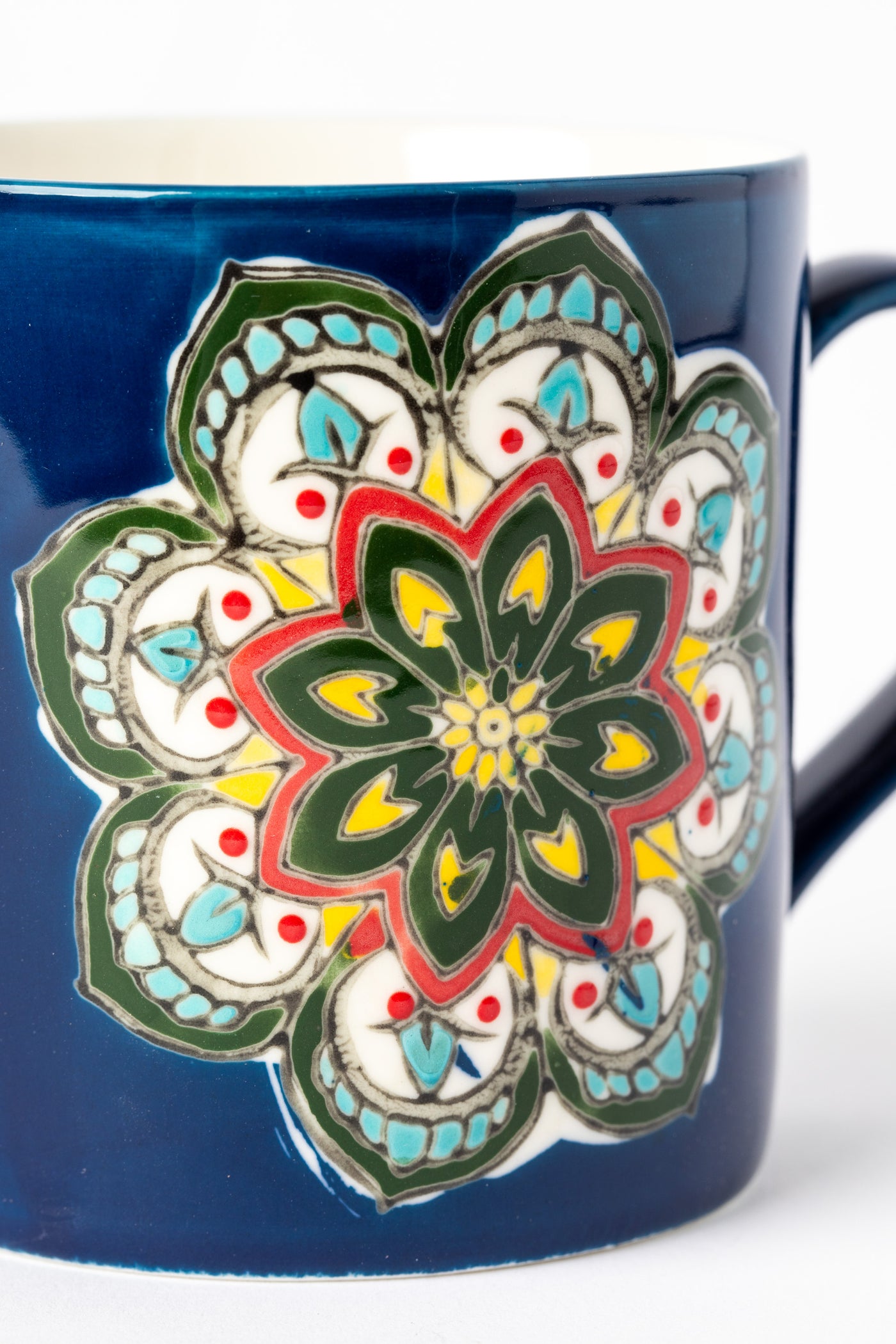 Close-up of hand-painted mandala details on blue ceramic mug.