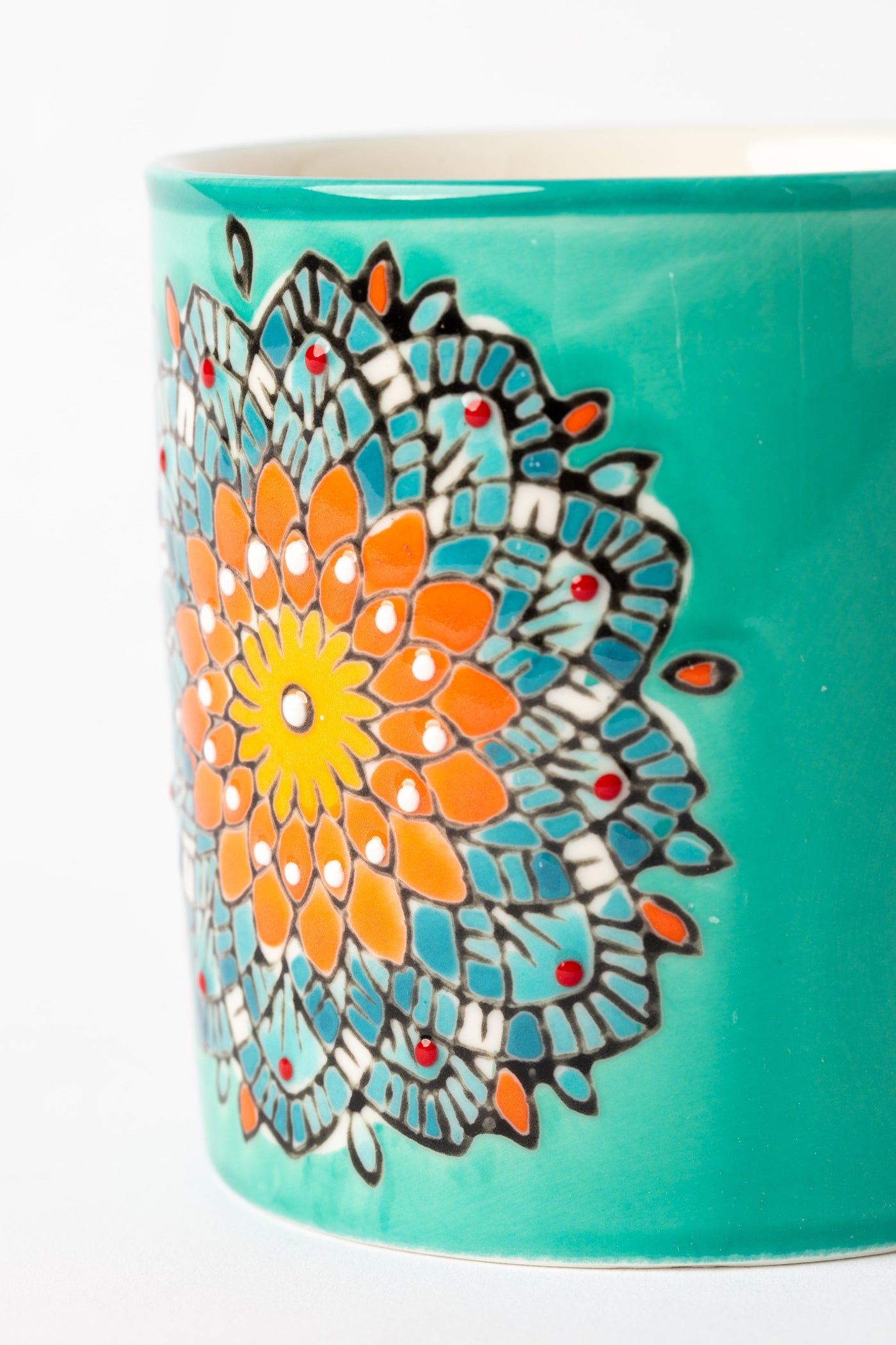 Close-up of hand-painted mandala details on turquoise ceramic mug.