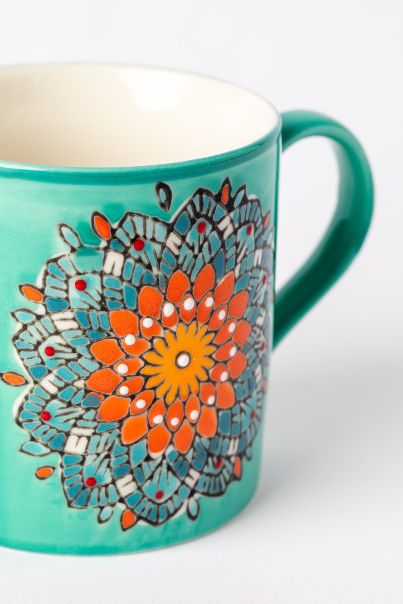 Close-up of hand-painted mandala details on turquoise ceramic mug.
