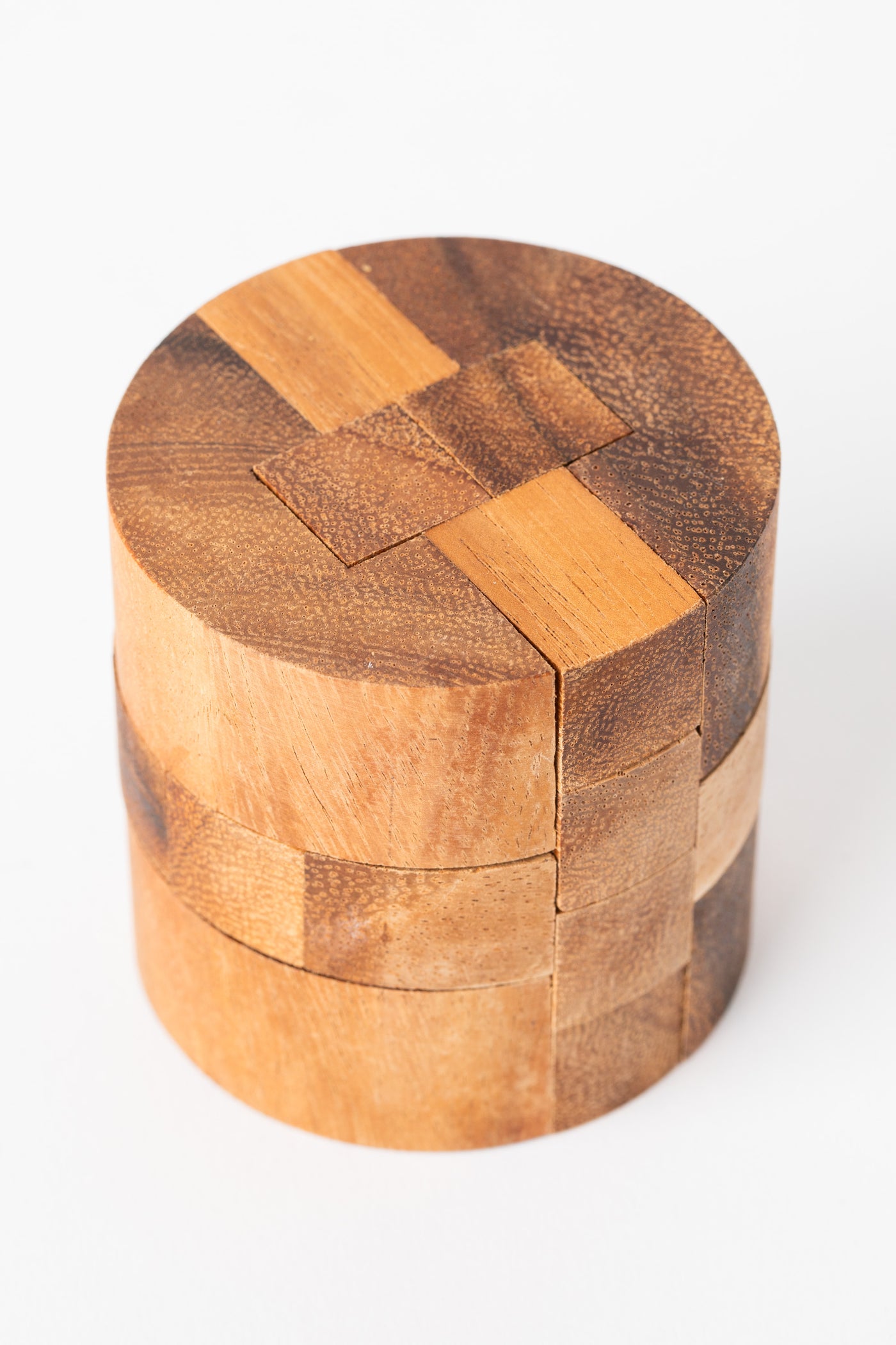 Cylindrical wooden puzzle handcrafted from natural wood blocks with interlocking segments.