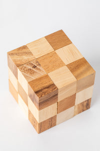 Handmade wooden cube puzzle made from natural light and dark wood blocks for a classic brain teaser look.