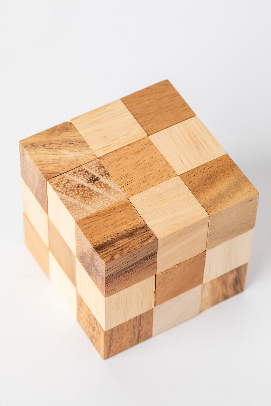 Handmade wooden cube puzzle made from natural light and dark wood blocks for a classic brain teaser look.
