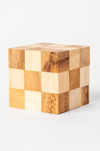 Handmade wooden cube puzzle made from natural light and dark wood blocks for a classic brain teaser look.