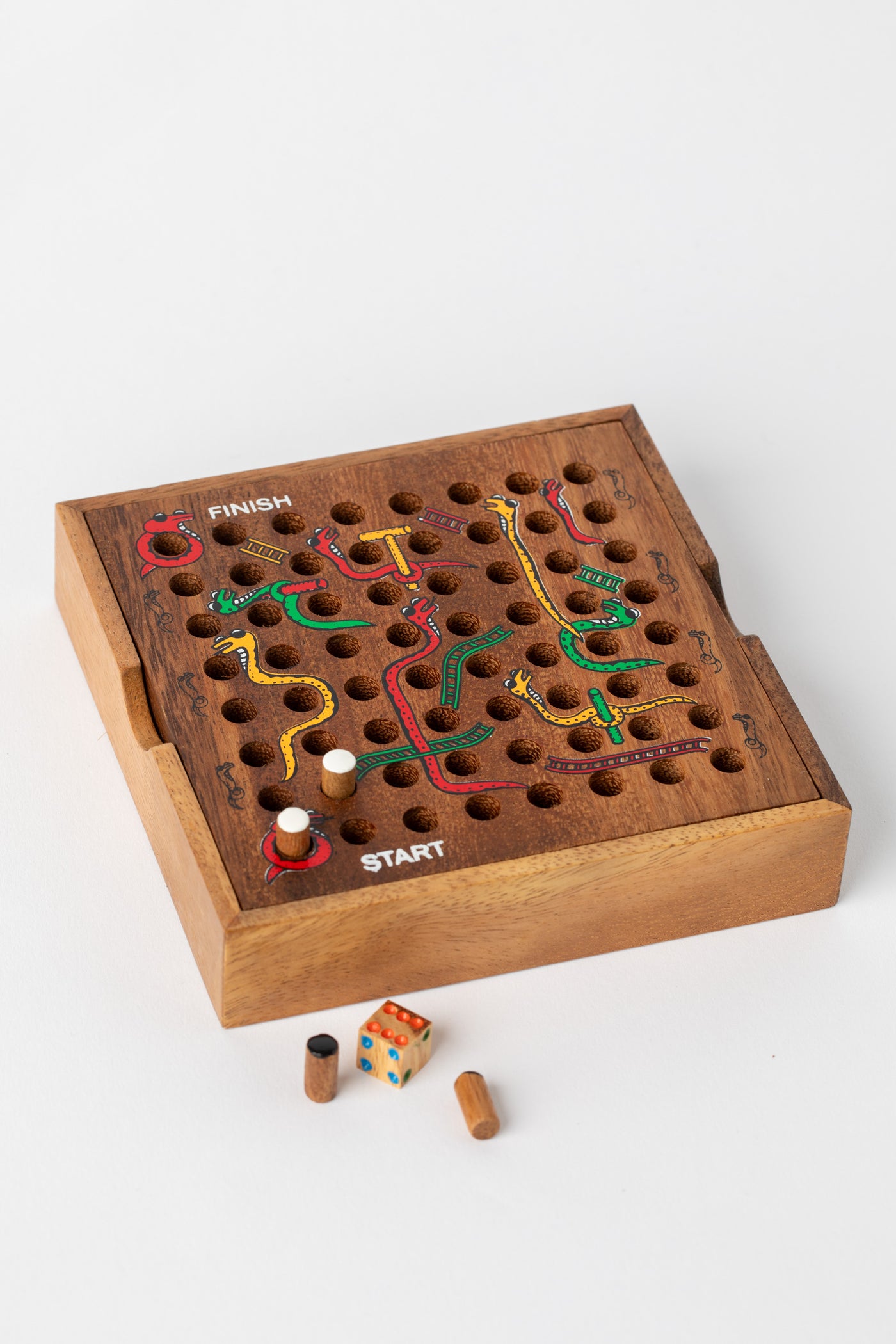 Handmade wooden snakes and ladders game board with colorful painted snakes and pegs — Slips and Strides wooden game handmade in Thailand.